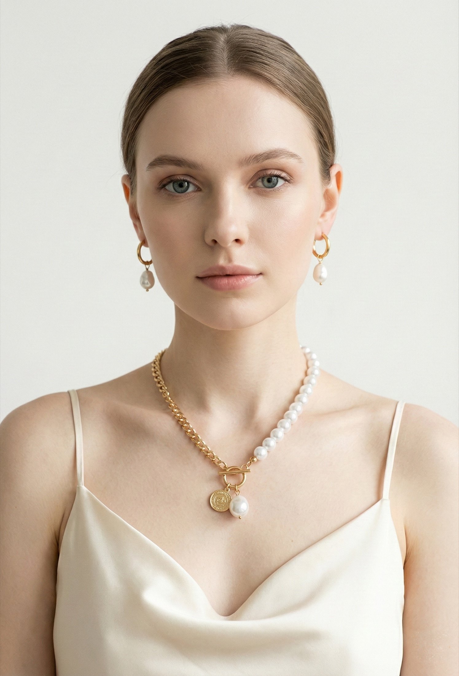 Model wearing a pearl and chain necklace on a pale ground